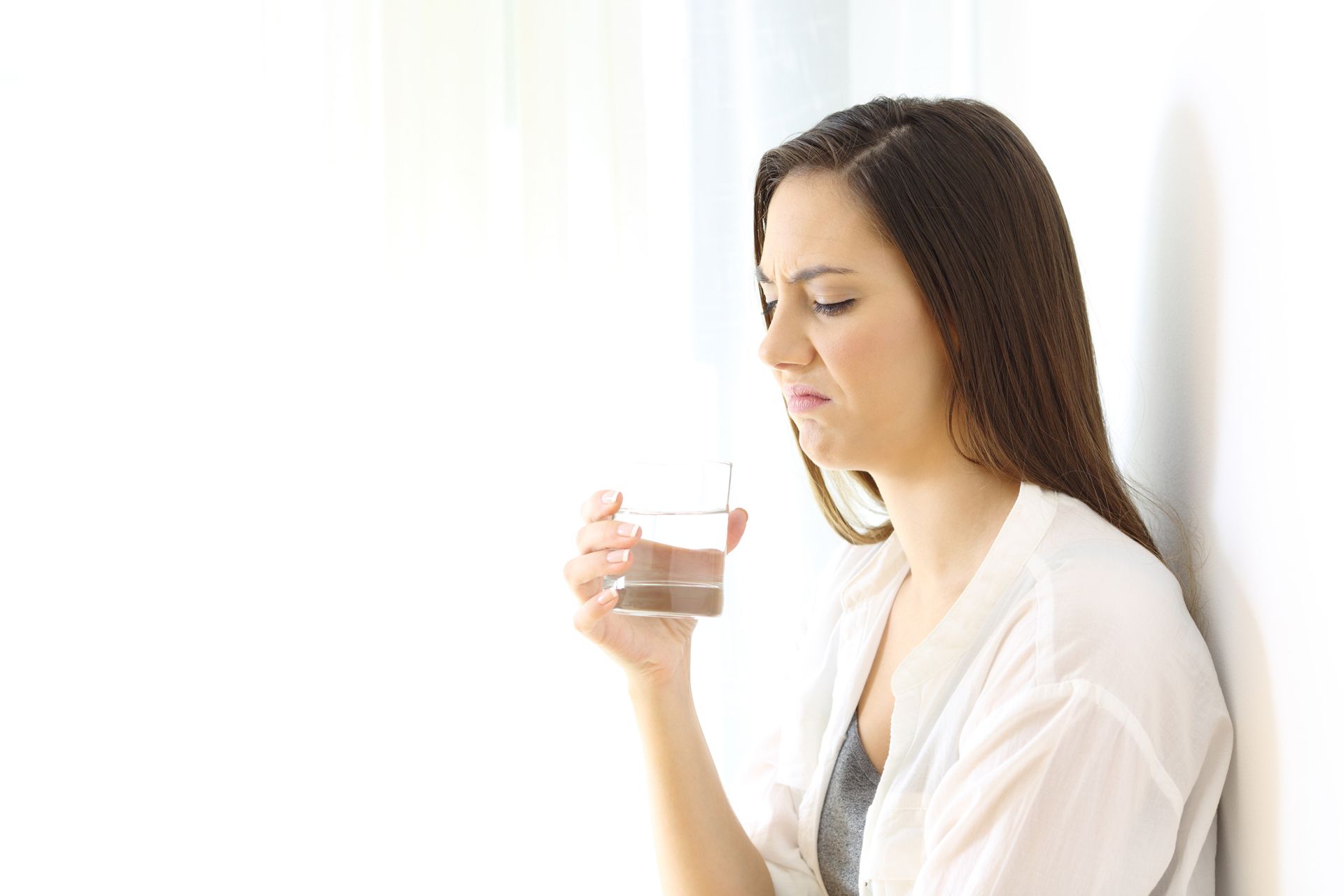 Bad Drinking Water, woman holding glass of water with a disgusted look on her face